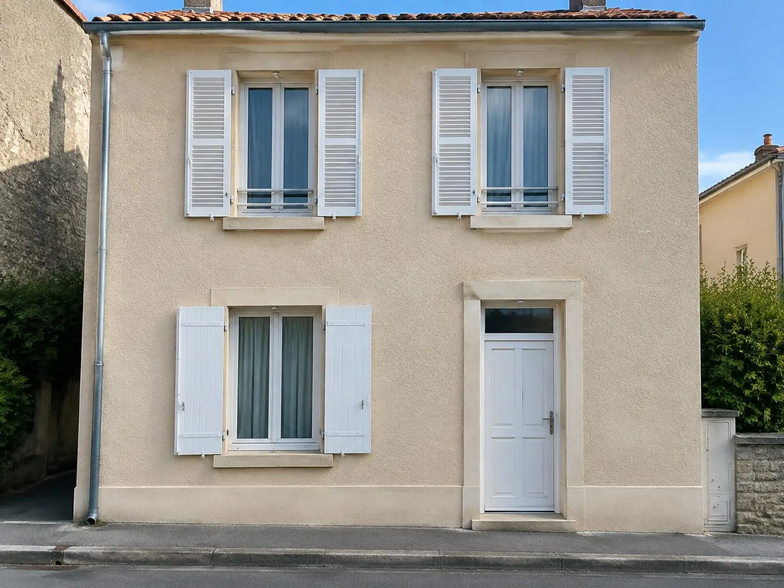 La même façade sous le même angle, l’enduit refait propre et uniforme : mêmes fenêtres, mêmes volets blancs, même porte.